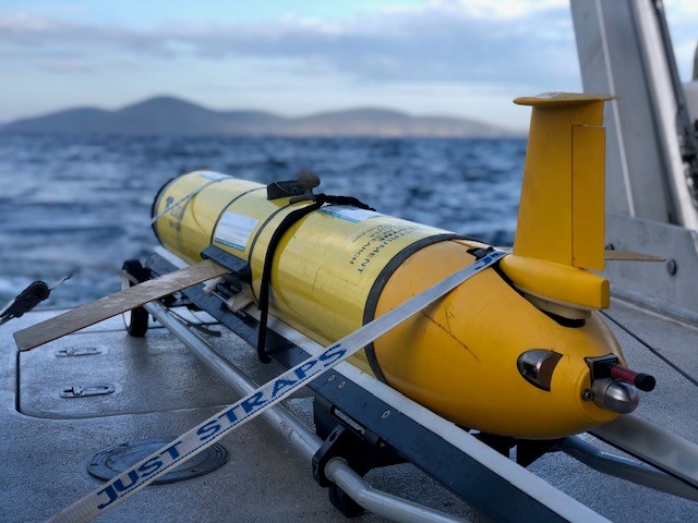 A yellow autonomous ocean glider on NSW Research Vessel Bombora with ocean in the background. 