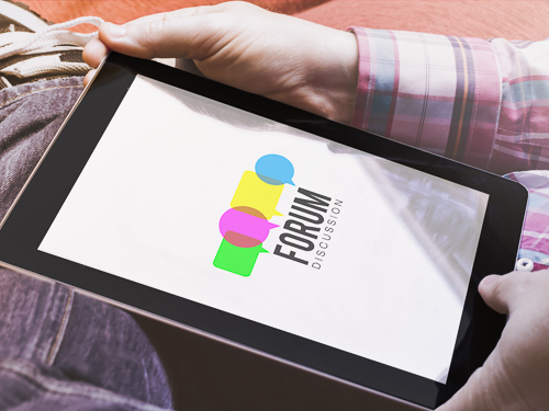 Looking down onto a tablet that is being held by a man. The tablet screen shows the words "Forum discussion" on a white screen and colourful speech bubble symbols.