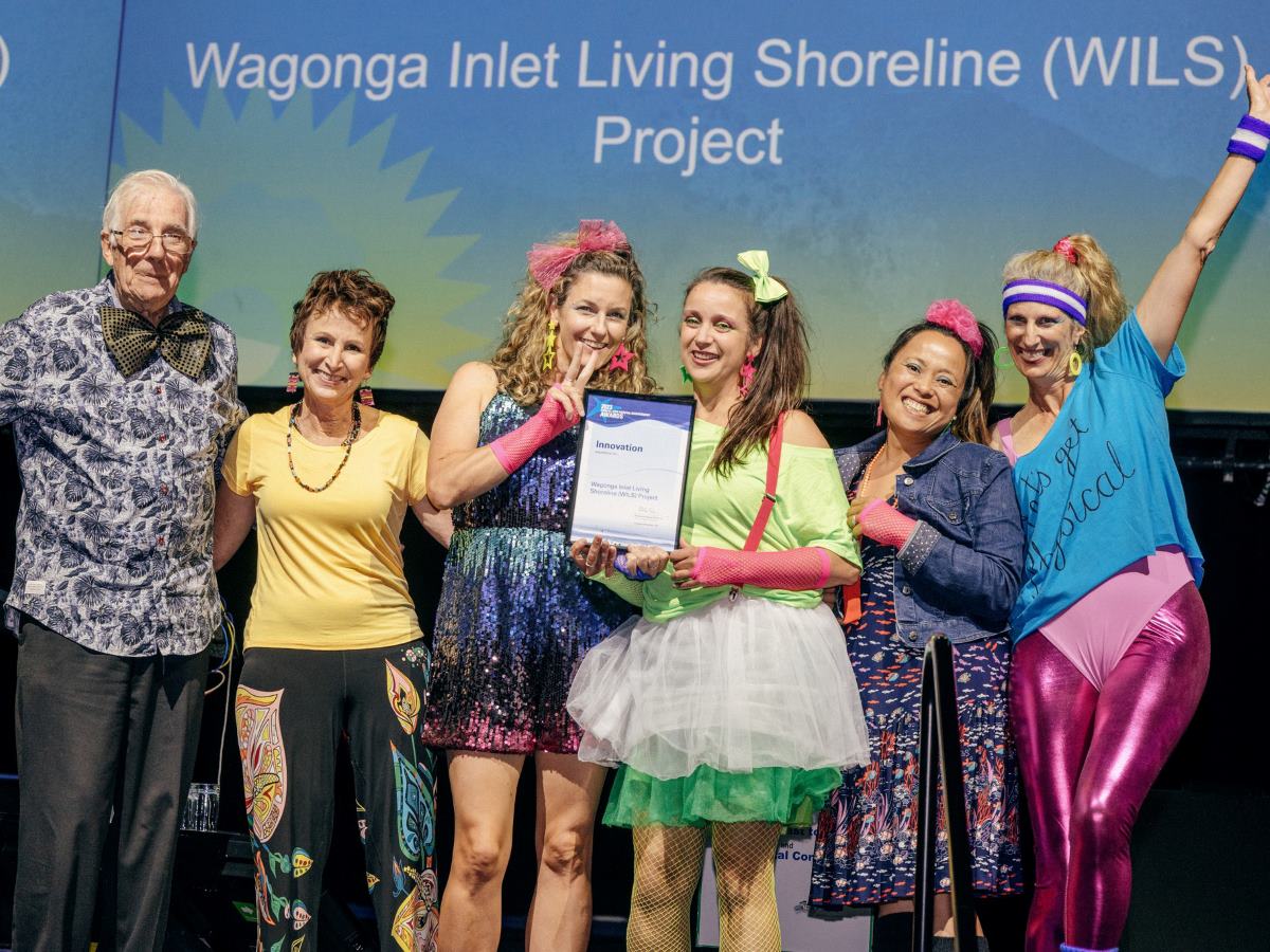 Six people on a stage holding award 