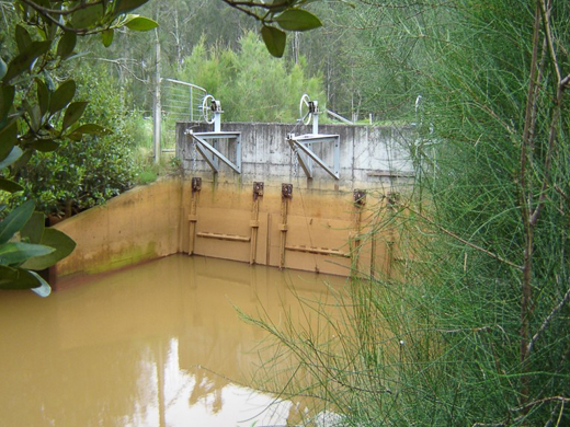 A downstream view of a floodgate with gates closed and iron staining from acidic water.