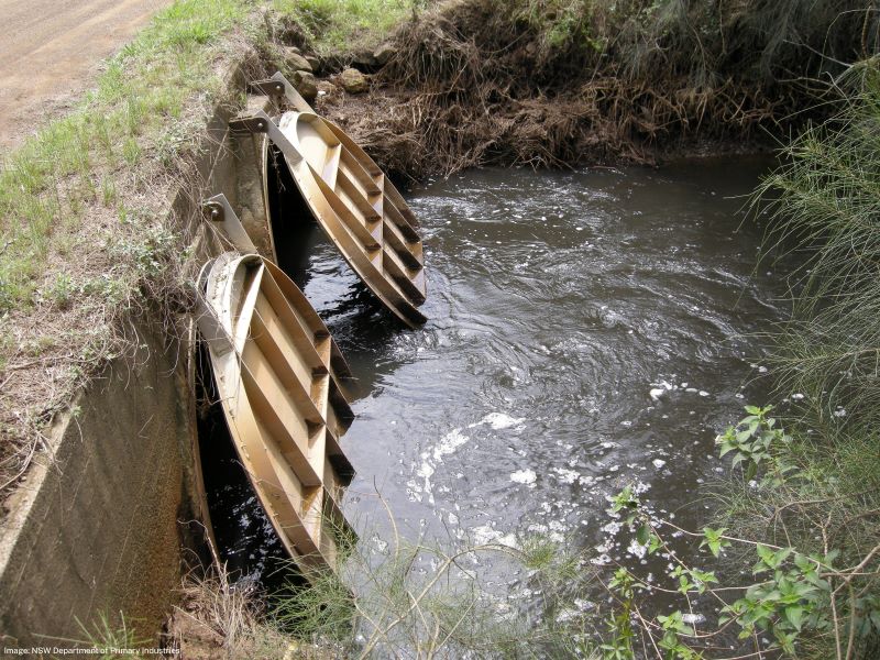 Two floodgate flaps slightly open in a channel with water flowing 