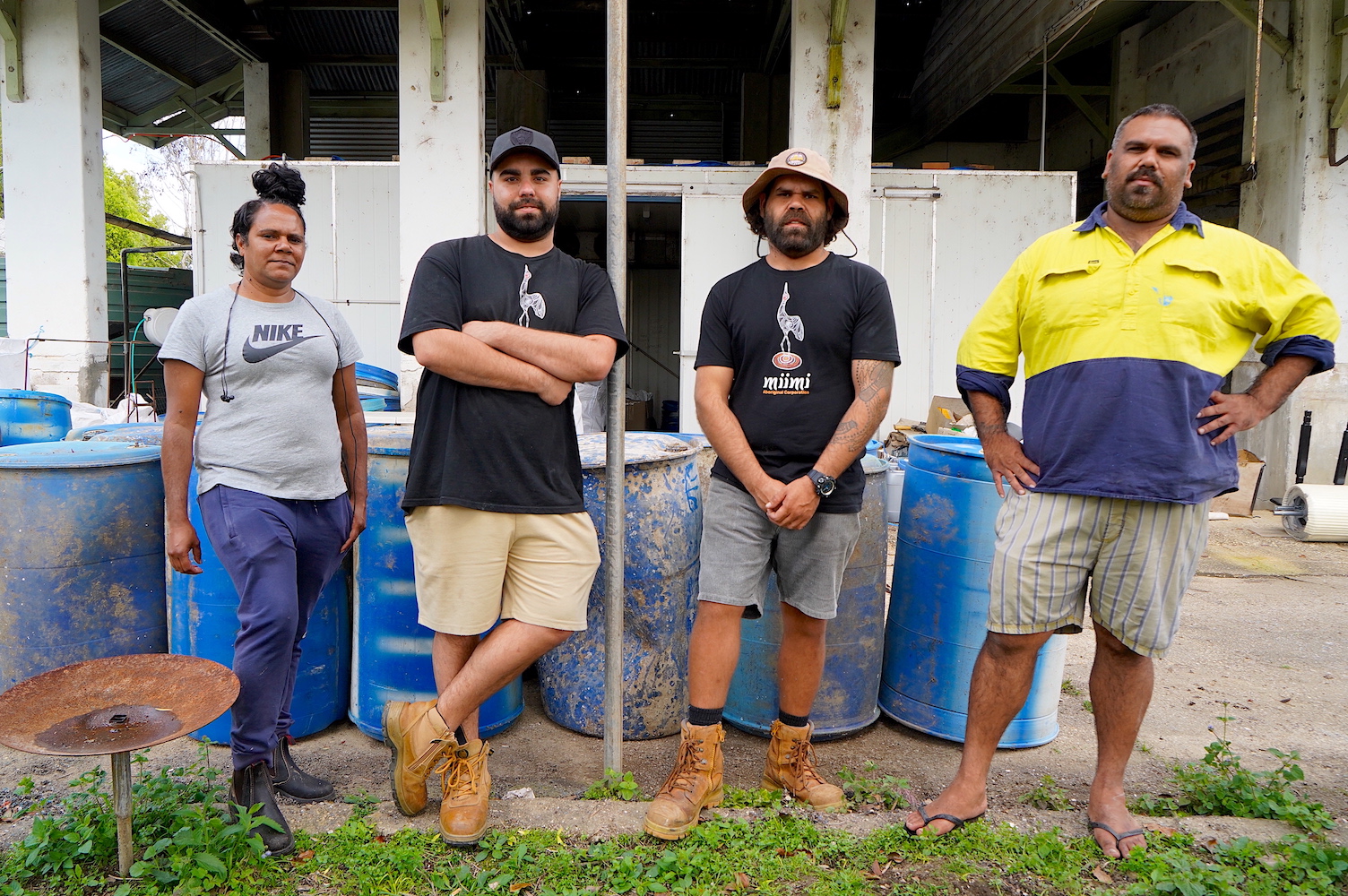 Four people standing in front of blue oyster barrels 